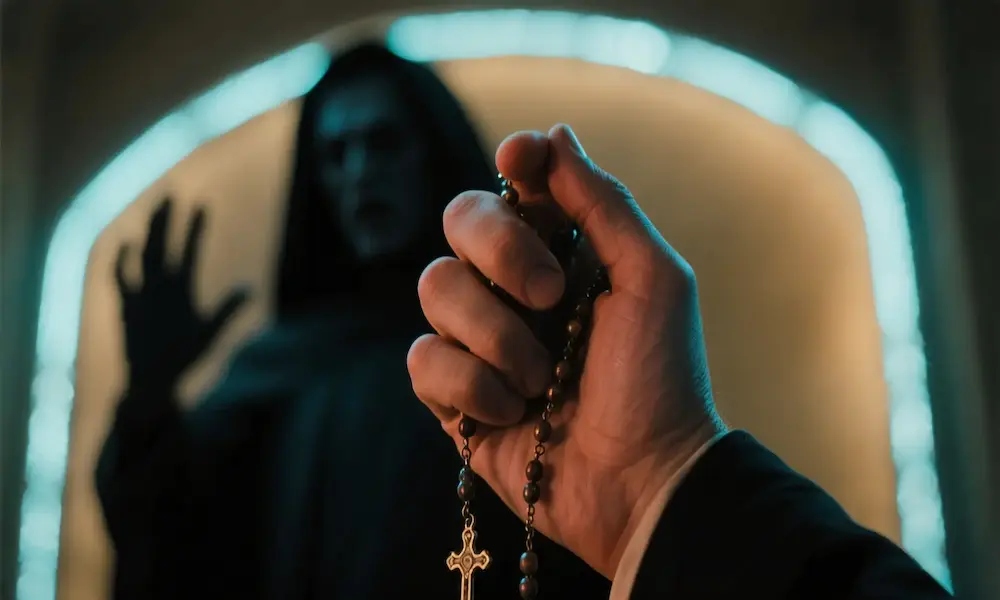 A shadowed mouth speaking mockery while hands clutch rosary beads.