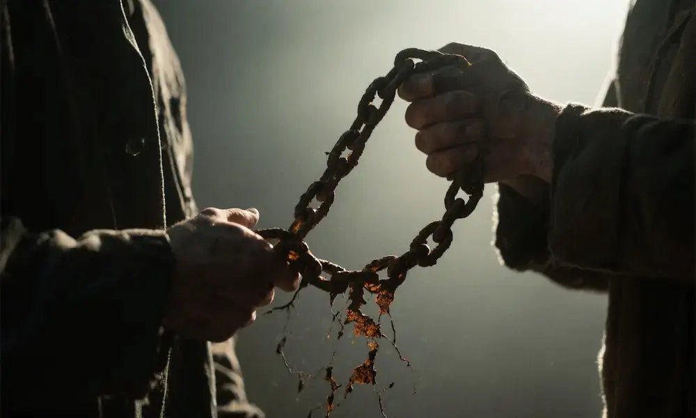 Half-lit figure holding a chain in shadow, symbolic of secret sin.
