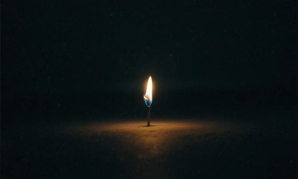 A single radiant flame burning in darkness, symbol of redemption.